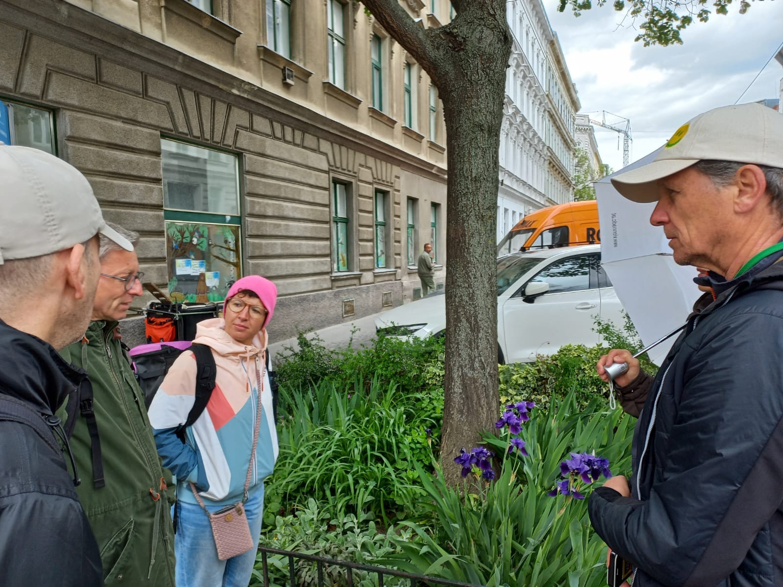 Frei Personen stehen rund neben einem Baum um den Blumen wachsen und reden miteinander
