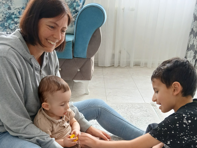 Eine Frau und zwei Kinder spielen am Boden 